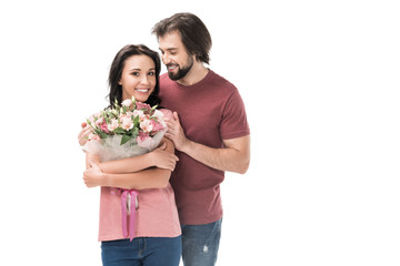 portrait of smiling woman with bouquet of flowers and husband isolated on white