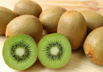 Heap of whole fruits and cross-sections of fresh kiwi fruits on the wooden table 