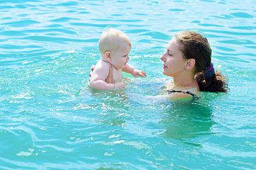 Mother  bathing her baby in azure  sea water