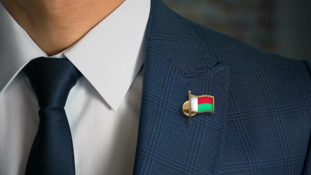 Businessman Walking Towards Camera With Country Flag Pin - Madagascar