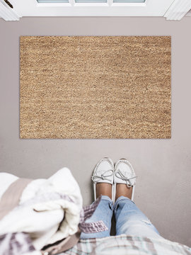 Blank Doormat Before The Door In The Hall. Mat On Gray Floor, Girl In White Shoes. Welcome Home, Product Mockup