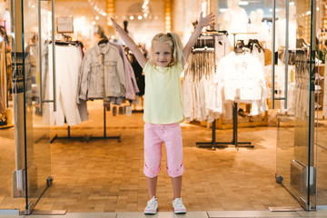 selective focus of happy little child standing with wide arms in shop