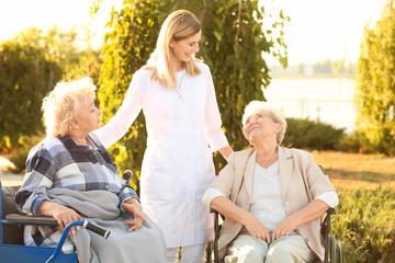 Nurse from care home walking with senior people outdoors