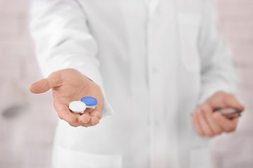 Doctor holding plastic container with contact lenses, closeup