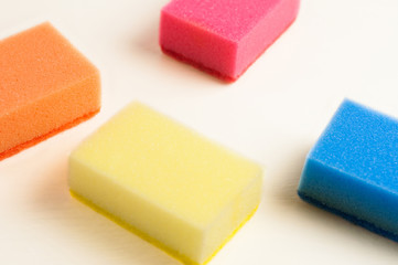 Scattered four red blue orange and yellow sponges for dishwashing on white background. Cleaning concept