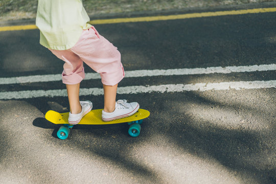 cropped image of little child riding on skateboard on running tracks