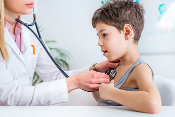 Pediatrician examining boy with stethoscope