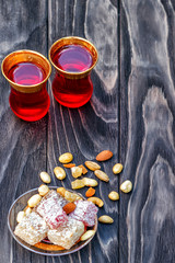 Traditional oriental sweets and traditional Turkish tea on a dark wooden background. Turkish desert-Rahat locum.