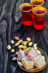 Traditional oriental sweets and traditional Turkish tea on a dark wooden background. Turkish desert-Rahat locum.