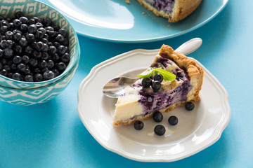 Tea time. Homemade blueberry cheesecake with ricotta cheese on blue paper background