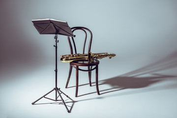 Music stand for notes and saxophone on chair in studio