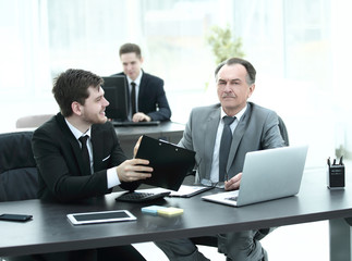 boss and employee discussing the document sitting at the Desk in the office.