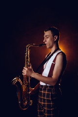 Obraz na płótnie Canvas side view of professional stylish young jazzman playing saxophone