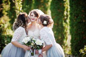 Happy bride posing with her bridesmaids outdoor with bouquets.