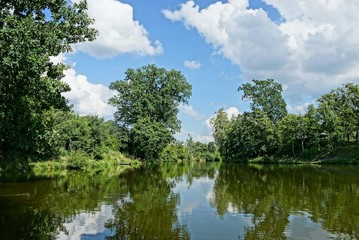 a large lake with green trees against the sky