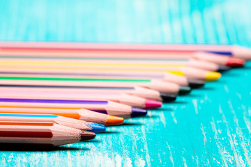 colored pencils in perspective on a wooden blue table, many colored pencils