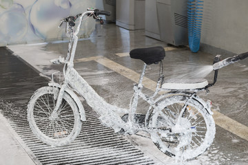 Washing an electric bicycle with a jet of foam in a car wash