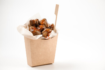 Isolated paper food bag filled with tasty chestnuts with sauce on white background