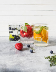 Set of summer healthy cocktails, various citrus infused waters, lemonades or mojitos, with lime and blueberries, orange and strawberries and basil in glasses