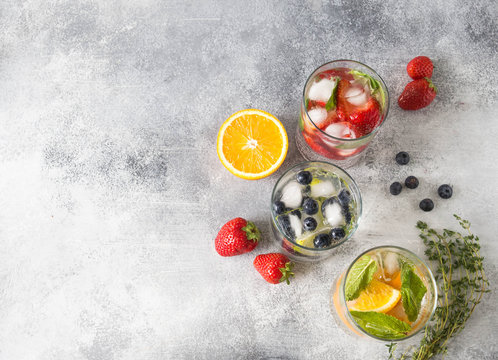 Set of summer healthy cocktails, various citrus infused waters, lemonades or mojitos, with lime and blueberries, orange and strawberries and basil in glasses, diet detox beverages,