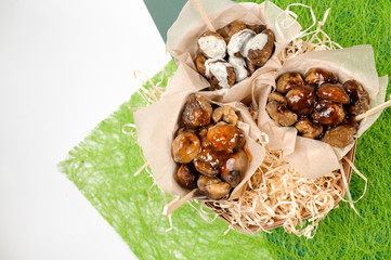 Top view of three paper packs with chestnuts on green background