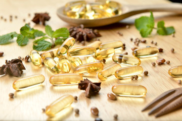 Medicine herb, Cod liver oil omega 3 gel capsules spread on top of woodwn desk with healthy...