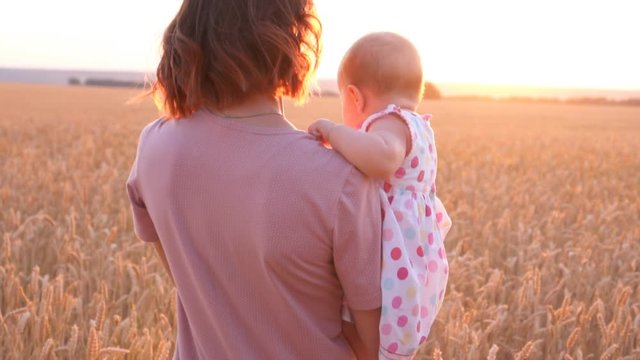 Loving mother with little daughter and walking in field