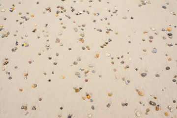 Top view of colorful stones on sand at the beach.