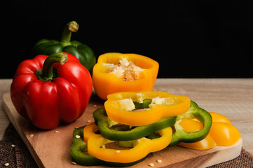 Colourful red,yellow and green peppers are placed on a wooden tray ready for cooking with black background,Selective focus