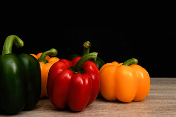 Colourful red , yellow and green peppers put on wooden table with black background,Selective focus