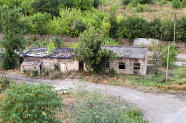 Two destroyed buildings among trees.