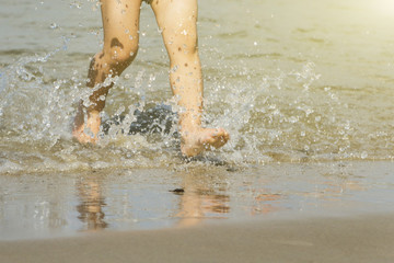 feet of boy running along the beach in the water.