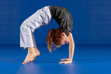 Young Girl Doing A Gymnastic Flip On Blue Background