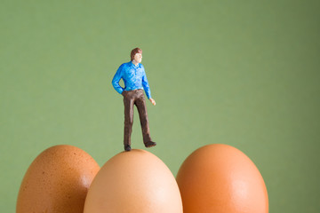 Walking on Eggshells - model figure on top of eggs - obrazy, fototapety, plakaty