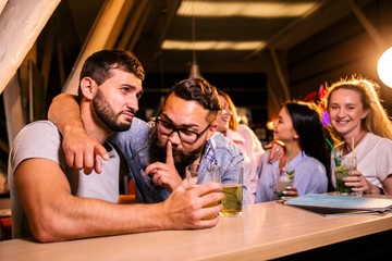 Two men with glasses of beer secret in the bar against the girls