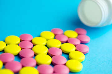 Heap of pills or tablets capsule plastic drugs bottle blue background. Pharmacy drugstore concept.