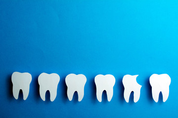 White healthy teeth over blue background  with copy space. Dental care and whitening teeth. Tooth restoration. Installation of the dental implant. Oral dental hygiene Concept.