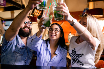 Friends spend a weekend in a nightclub, holding up a glass of Mojito up