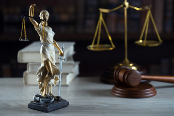 Justice Themis goddess sculpture on dark brown background.