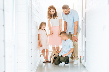 parents and children looking at adopted pug dog in corridor of animals shelter