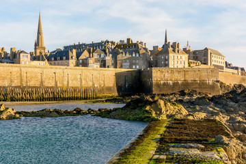 The walled city of Saint-Malo, France, at sunset with the steeple of the cathedral sticking out...