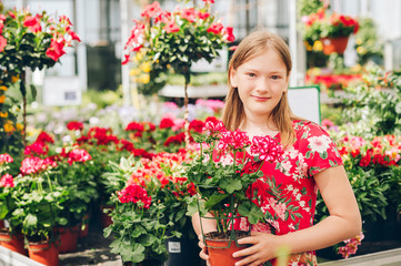 Adorable little girl choosing flowers in garden center