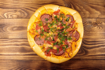 Homemade delicious pizza with salami, tomatoes and dill on wooden table. Top view