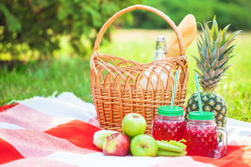 Fototapeta na wymiar picnic basket, fruit, juice in small bottles, apples, milk, pineapple summer, rest, plaid, grass Copy space