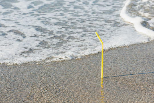 Plastic colored straw tubules for drinking in the sand on the beach. Concept