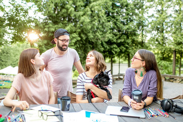 Friends having fun together sitting with dog during a study outdoors at the park cafe