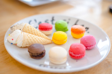 close up Mix color of macaroon on wihte plate with french language put on soft wooden table