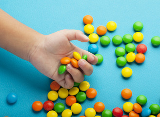 Close up of children hands and colorful candies on blue background