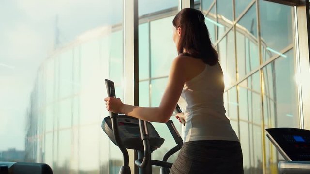slender girl on the treadmill in the stylish gym ,sun