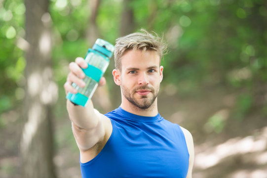Towards a healthier lifestyle. Athlete drink water after training in park. Man athletic appearance holds bottle with water. Man athlete cares about water balance. Sport and healthy lifestyle
